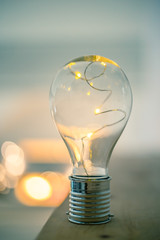 Ideas and innovation: Light bulb with LEDs is lying on a wooden table. Spot lights in the blurry background.