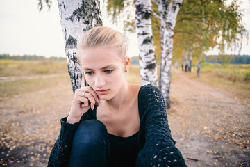 A young girl in black walking in the Park talking on the phone.