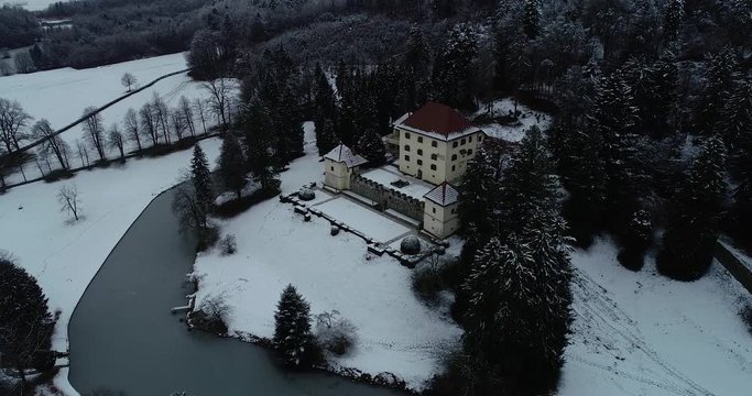 Slow right side rotating drone aerial view of an old castle and it's surroundings covered in snow.