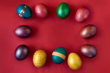 Painted colorful eggs on a red background in the Easter holiday. Place for text.