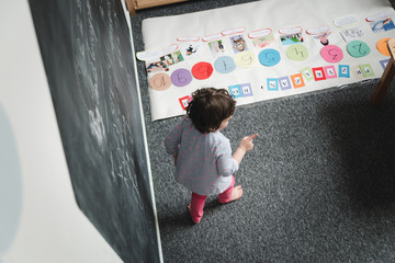 Little cute girl is drawing on blackboard and having fun in kindergarten. Daycare concept.