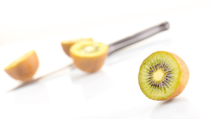 Green fresh kiwi fruit cut into half and knife on a white background