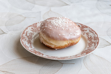 Traditional Polish donut known as paczek. Paczek with frosting with coconut flakes.