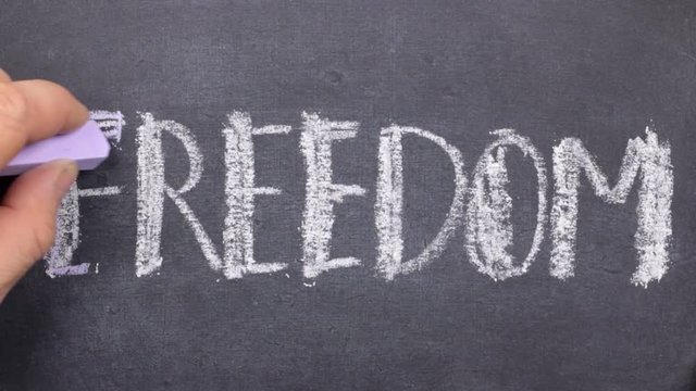 Word FREEDOM, written by hand in chalk on a blackboard.