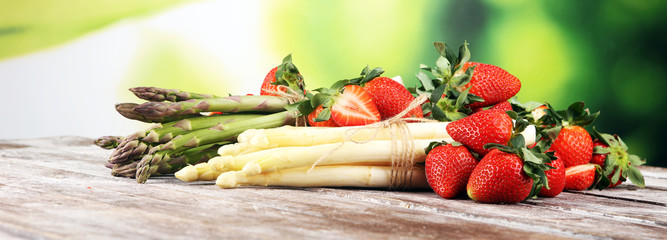 White and green asparagus with strawberries on wood - obrazy, fototapety, plakaty