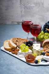 cheese plate, ciabatta, fresh grapes and two glasses of red wine, vertical