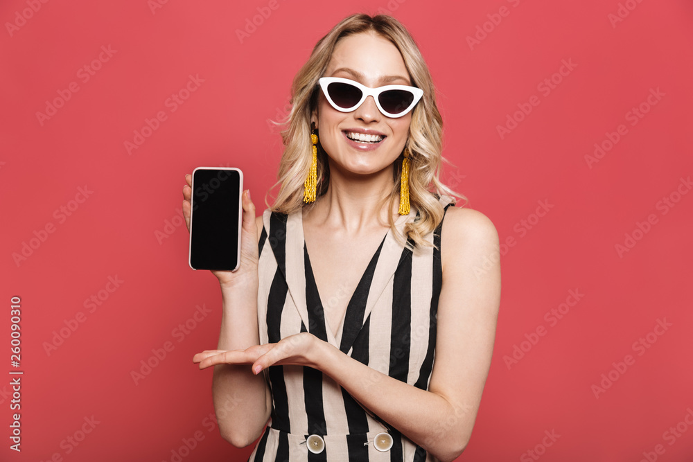 Sticker beautiful amazing young woman posing isolated over red coral background showing display of mobile ph