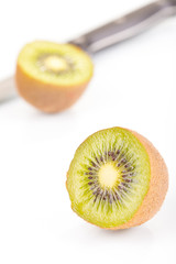 Green fresh kiwi fruit cut into half and knife on a white background