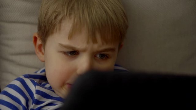 capricious child boy is nervous and playing video game by tablet