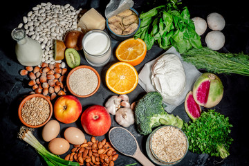 Foods rich in calcium such as sardines, bean, dried figs, almonds, cottage cheese, hazelnuts, parsley leaves, broccoli, italian cabbage, cheese on dark background