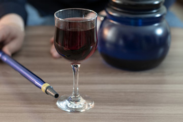 Hookah and a glass of red wine on the table.
