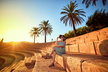 Young beautiful woman in beach hat sitting on the steps of an ancient amphitheater at sunny day in Bodrum, Turkey. Vacation Outdoors Seascape Summer Travel Concept