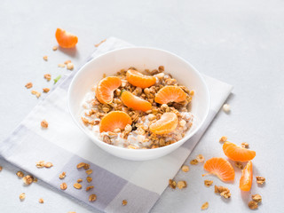 Healthy breakfast. Baked muesli with tropical fruits, fresh tangerines and yogurt on white background