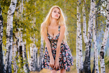 An attractive girl with long hair in a short dress walks in the Park.