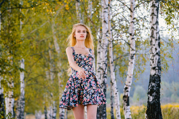 An attractive girl with long hair in a short dress walks in the Park.