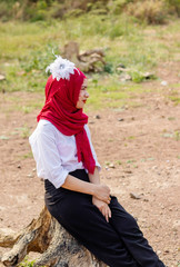  Women muslim, women islamic,wearing a red fabric head covering adorn with white fabric flowers wear shirt white sit poses photography on the Stump before to ramadan month.