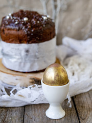 Amazing Chocolate Easter Cake with chocolate drops and dry cherries on an old wooden background with black and golden eggs. Easter concept. Selective focus, close up, copy space.