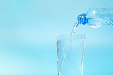 Drinking water pouring into a glass on a blue background