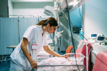 Female doctor examining newborn baby in the hospital. Night shift - obrazy, fototapety, plakaty