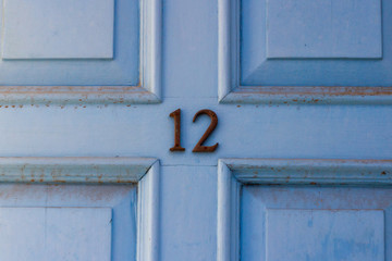 Light sky blue house door number 12 with the twelve in dark metal