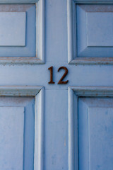 Light sky blue house door number 12 with the twelve in dark metal