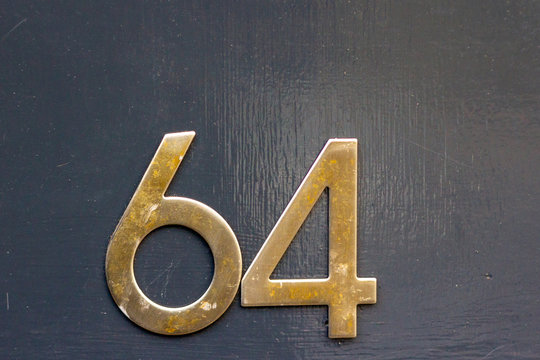 House number 64 with the sixty-four in large brass numbers on a painted wooden door