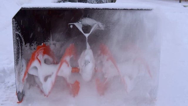 The spinning blades of the snowblower are milling much snow.