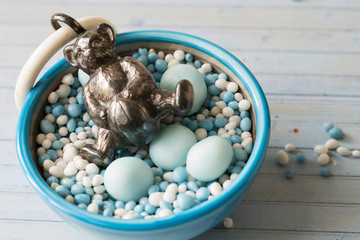 blue white aniseed balls , Dutch Muisjes, in bowl.  With silver bear rattle. Traditional sprinkles for when a baby boy is born, in The Netherlands