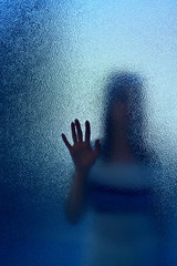 silhouette of a woman through frosted translucent glass