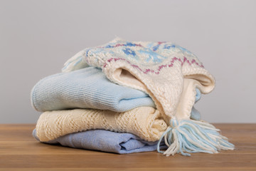 different sweaters on a wooden table on a light background. Autumn and winter clothes.