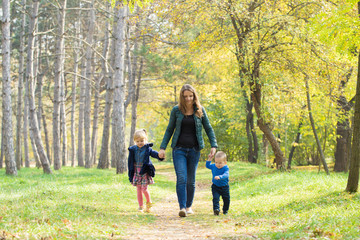 Mom, son and daughter walking in the park at sunset