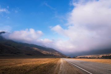 mountain road with low clouds and blue sky