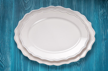 Two empty white serving dishes on a blue wooden background, top view. Can be used as a mock-up.
