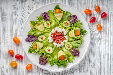 Plate of healthy vegetable salad on white wooden background. Top view