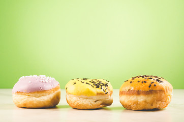 Donuts. Assorted donuts lying on a white table on green background. Сoncept sweet food