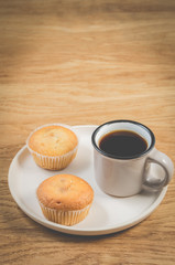 coffee break. Cup of the black coffee and cupcakes on a white tray, wooden table. Breakfast concept