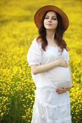 Pregnant woman in a dress in a field of flowers