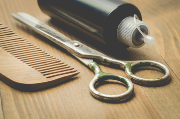 barbershop concept. Hairbrushes, sprayer and a scissors on a wooden board, selective focus