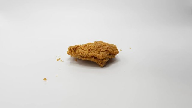 Pieces of crumbed chicken dropping one by one