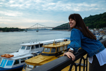 young pretty woman looking on river at morning time. boats in dock