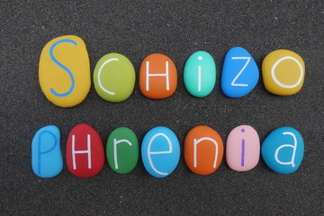 Schizophrenia text composed with multi colored sea stones over black volcanic sand