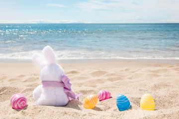 Easter bunny with color eggs on the ocean beach