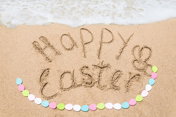 Happy easter lettering background with eggs on the sandy beach