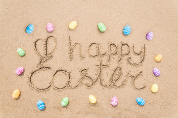 Happy easter lettering background with eggs on the sandy beach