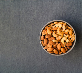 Healthy breakfast. Cashews and almonds in blue bowl on gray background. 