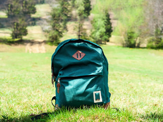 Green tourist backpack  on lawn background in the mountains. Travel concept in the wild. 