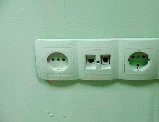 Old electrical outlets on green wall