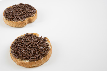 Traditional breakfast in The Netherlands: rusk with chocolate sprinkles, Dutch Hagelslag, against white background. Space for text