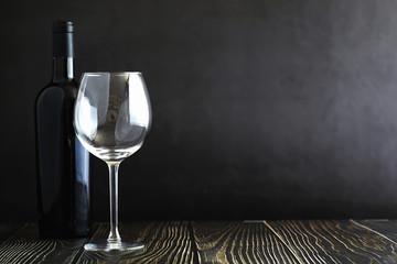 A glass of red dry wine on the table. Dark bottle and glass of wine.