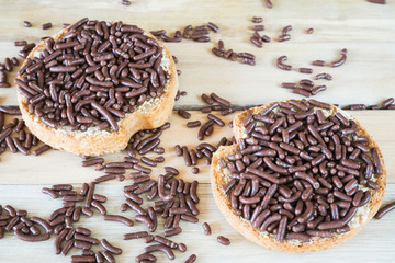 traditional breakfast in The Netherlands , chocolate hail, hagelslag, on rusk against wooden background